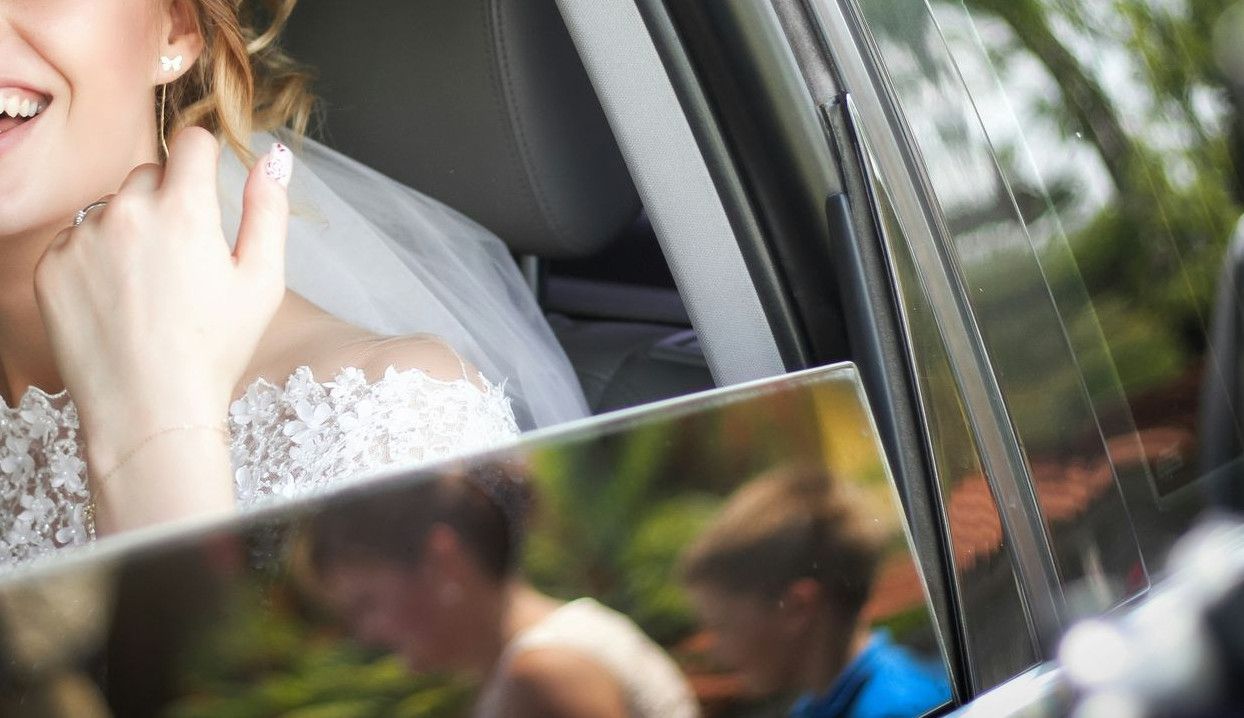 woman wearing wedding dress smiling inside car